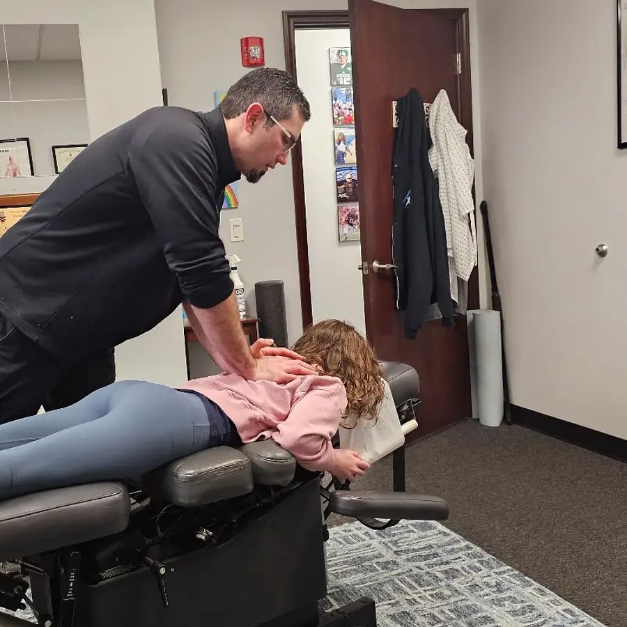 A doctor adjusting a younger patient on the table